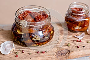 Sun dried tomatoes with thyme and sea salt in an olive oil in a glass jar on the old wooden background. Selective focus.