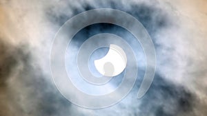 Sun eclipse (partial) with a cloudy sky around
