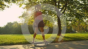 SUN FLARE: Golden sun rays shine on young woman riding an electric longboard.