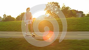 SUN FLARE: Happy female rider enjoying a fast ride on her electric longboard.