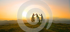 SUN FLARE: Mountain biking friends high five after reaching summit at sunrise