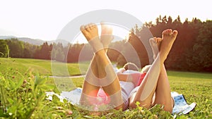 SUN FLARE: Unrecognizable barefoot man and woman lie in the serene countryside