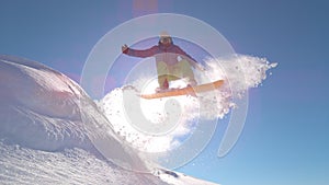 SUN FLARE: Young snowboarder performs epic jump on perfect powder snow slope.