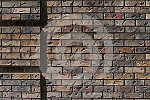 Sun glances off a brick wall with impressions giving it texture background