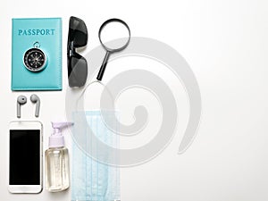 Sun glasses,sanitizer bottle,mask,passport,smartphone,ear buds,passport  and compass isolated on white background with copy space.