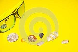 Sun glasses sea shells bright yellow background. Concept summer holidays travel