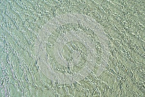 Sun glitter on shallow water over sand ripples by low tide