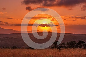 The sun glows behind clouds in an intense sunset above an Africa