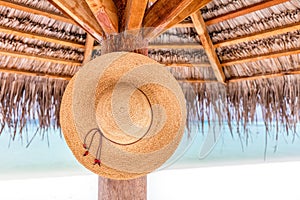 Sun hat hanging on sunshade umbrella on tropical beach. Maldives.