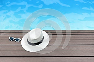 Sun hat and sunglasses on a wooden pier view.