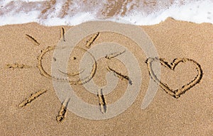 Sun and heart drawn on the sand