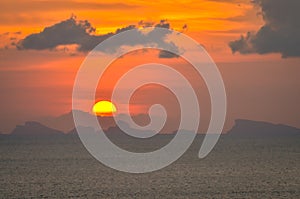 Sun hides behind clowds dramatic and colorful sunset at beach photo
