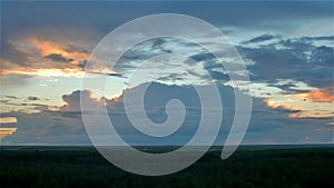 Sun hides behind storm rain cloud over green summer forest. aerial timelapse