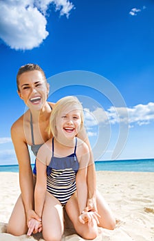 Happy young mother and daughter on seacoast having fun time