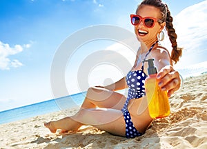 Smiling fit woman in beachwear on the seashore with sun cream