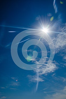 Sun with lens flare, on blue sky background.