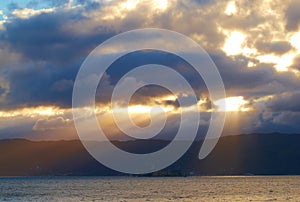 Sun light breaking through dark cloudy copyspace over a calm ocean. Sunlight shining through thick clouds in the early photo