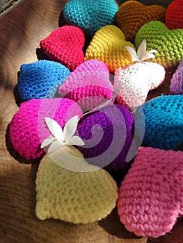 Sun light on falling flower and leaf on colourful hearts in wooden tray in the garden