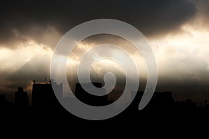 Sun light shine through dark cloud with silhouette of building