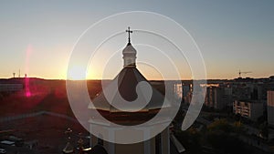 The sun looking out from behind church dome. Aerial shot. Sunset.