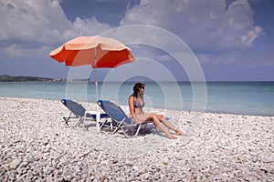 Sun lounger and umbrella on empty rock beach