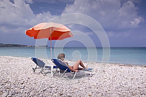 Sun lounger and umbrella on empty sandy beach