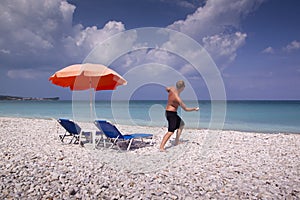 Sun lounger and umbrella on empty sandy beach