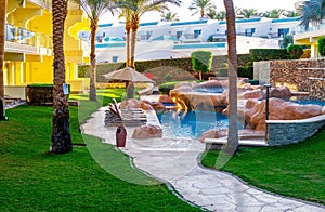 Sun loungers and blue clear water in the swimming pool. Tropical resort