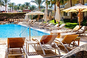 Sun loungers and blue clear water in the swimming pool. Tropical resort