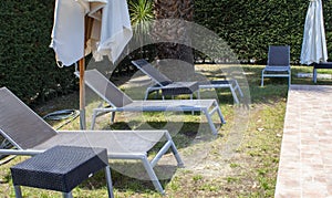 Sun loungers by the Hotel pool. A Place to Relax After Work. Comfortable Armchairs and Sun Umbrellas Against the Backdrop of Green