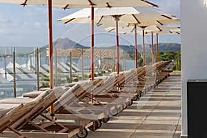 Sun loungers near pool with umbrella parasol beautiful sunny day