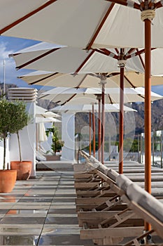 Sun loungers near pool with umbrella parasol beautiful sunny day