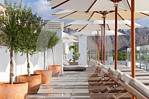 Sun loungers near pool with umbrella parasol beautiful sunny day