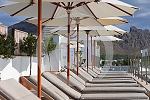 Sun loungers near pool with umbrella parasol beautiful sunny day