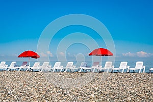 Sun loungers and red umbrellas on the beach in Batumi