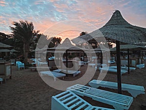 Sun loungers and straw umbrellas and beautiful sunset on the beach of Hurghada, Egypt