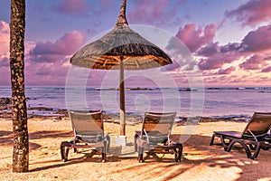 Sun loungers and umbrella on the sea beach at evening, beautiful sunset on the Mauritius island