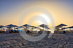 Sun loungers with umbrellas on the beach in Marsa Alam at sunrise, Egypt