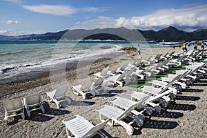 Sun loungers and umbrellas on the pebble beach in the resort of Kabardinka, Krasnodar region, Black sea.