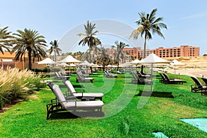 Sun loungers and umbrellas on sea beach on sunny day. One of best resorts in the Gulf of Oman