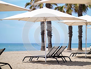 Sun loungers under white beach umbrellas near the sea, vacation concept