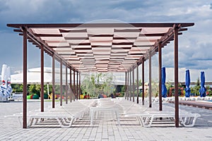 Sun loungers under a canopy. Deck chairs near the pool. A row of sun loungers.