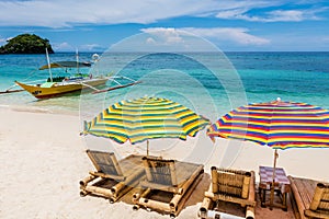Sun lounges with umbrellas at Ilig Iligan Beach, Boracay Island, Philippines