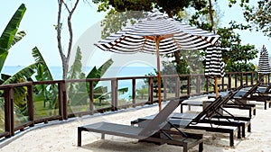 Sun lounges and umbrellas on sand in modern resort with sea view. Concept of tropical vacation, summer holidays. Relax