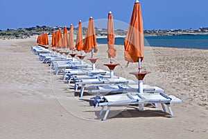 Sun orange beach umbrellas with white plastic chairs