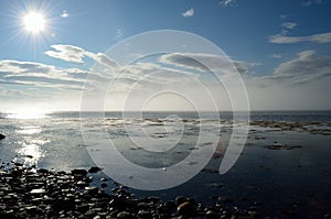 Sun over blue ocean and blue sky with heavy moving ocean mist