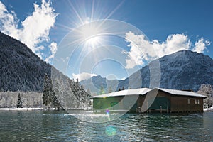 Sun over boat house at sunny and snowy winter day