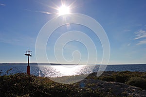 Sun over the sea. Coastline at Povljana beach on the island of Pag, Croatia. Small lighthouse