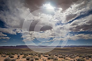 The sun peaking through the clouds in the desert