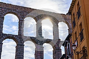 Sun peeking out between the arches of the Roman aqueduct of Segovia, Spain.